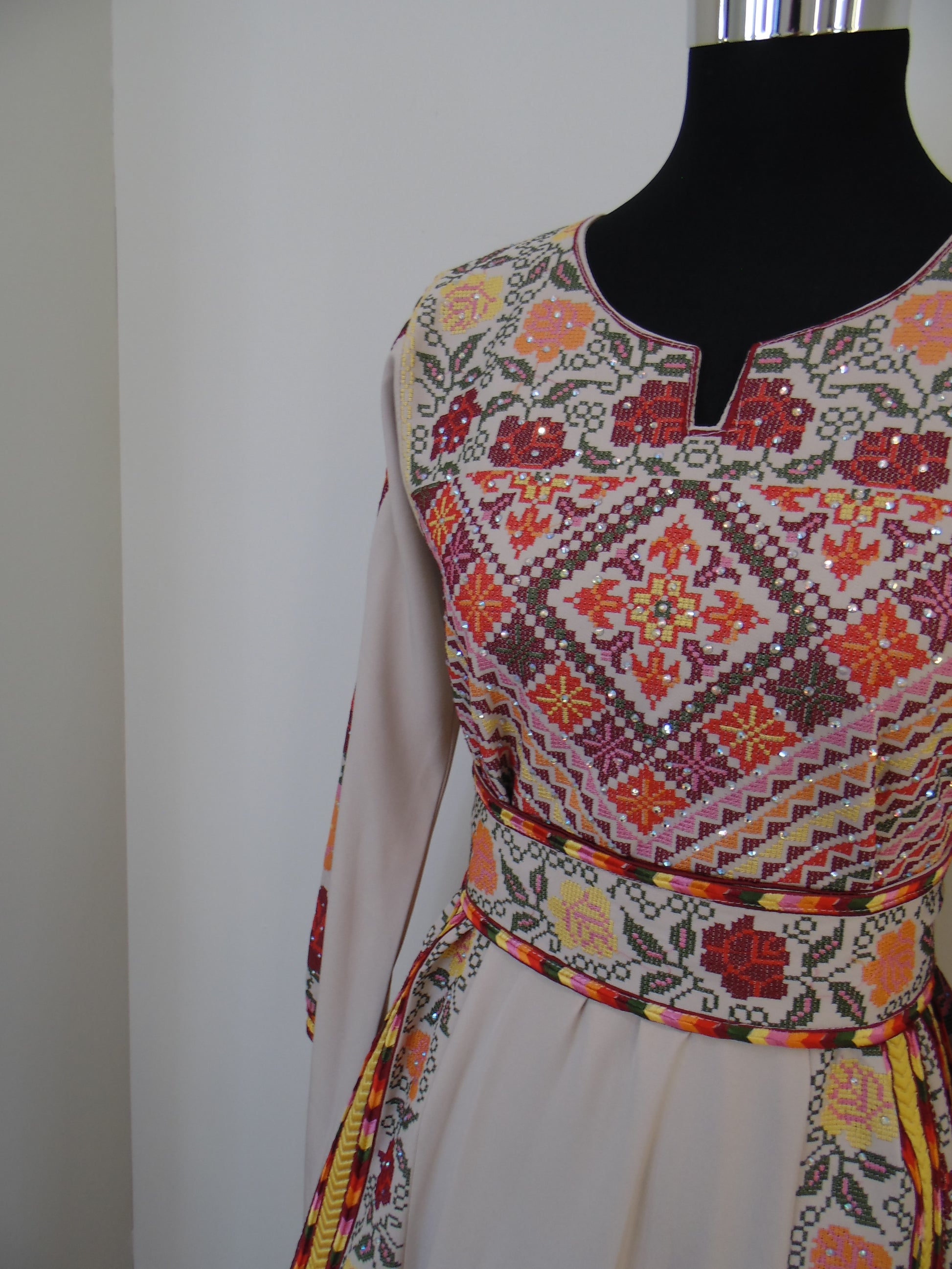 Colorful embroidered fabric with geometric patterns on a white background