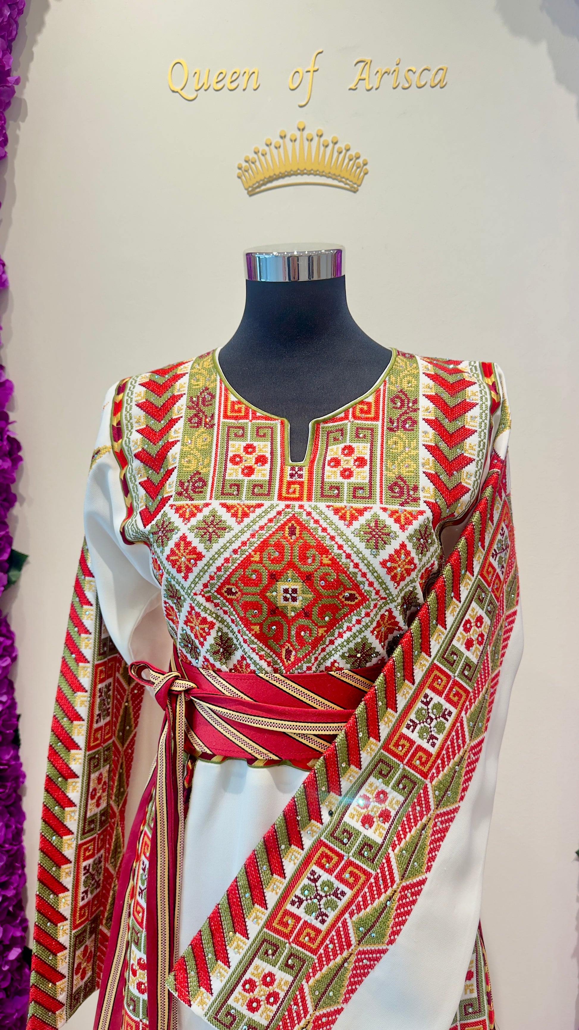 Mannequin wearing a traditional outfit with intricate patterns on a plain background