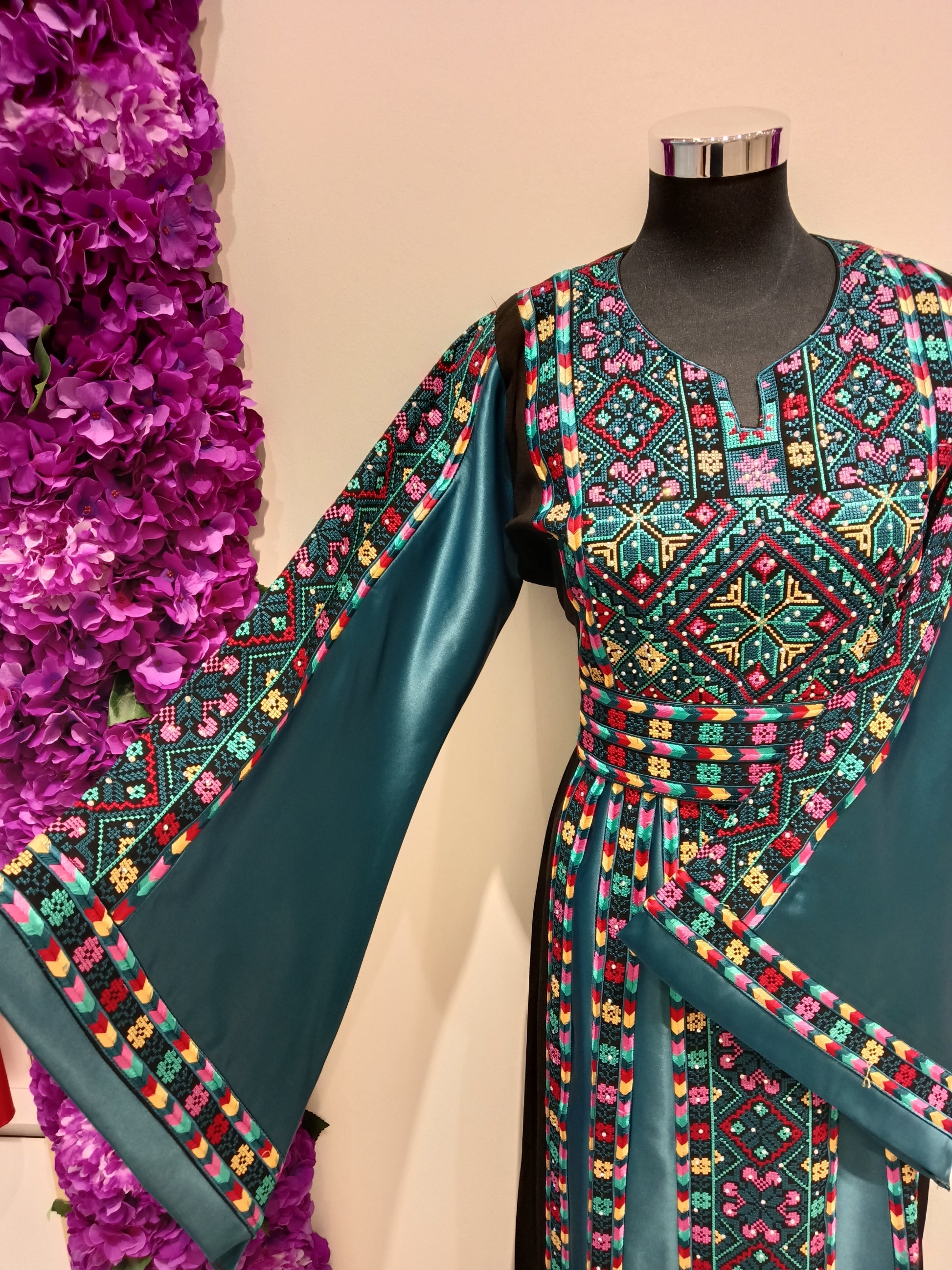 deep turquoise Palestinian thobe, beautifully contrasted with vibrant multicolor embroidery in shades of pink.
