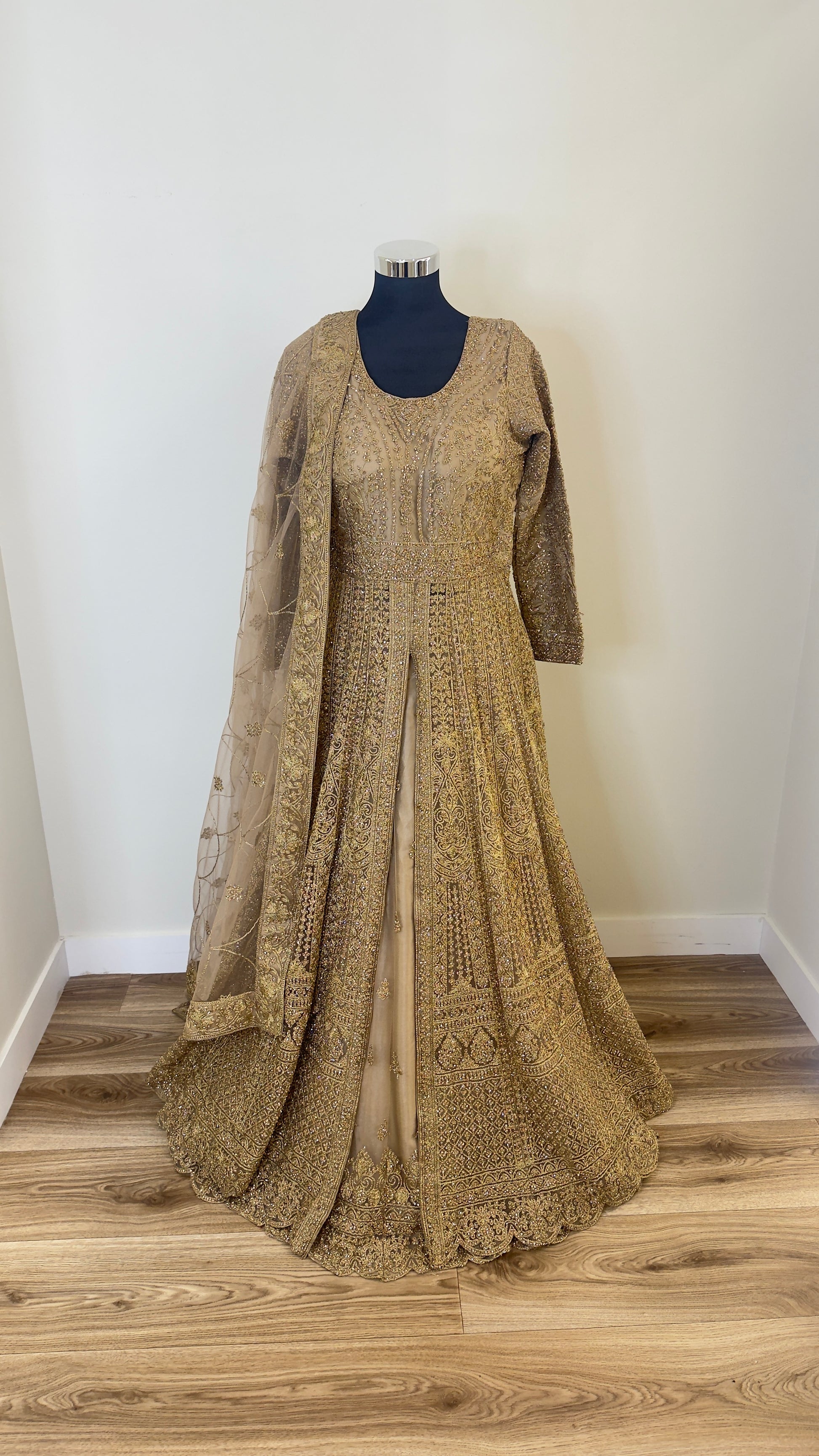 Long embroidered dress on a mannequin against a white wall.