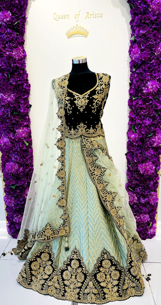 A traditional Indian lehenga choli dress . The outfit features a green embroidered choli with gold detailing, a light mint green skirt with gold embroidery, and a sheer mint green dupatta.