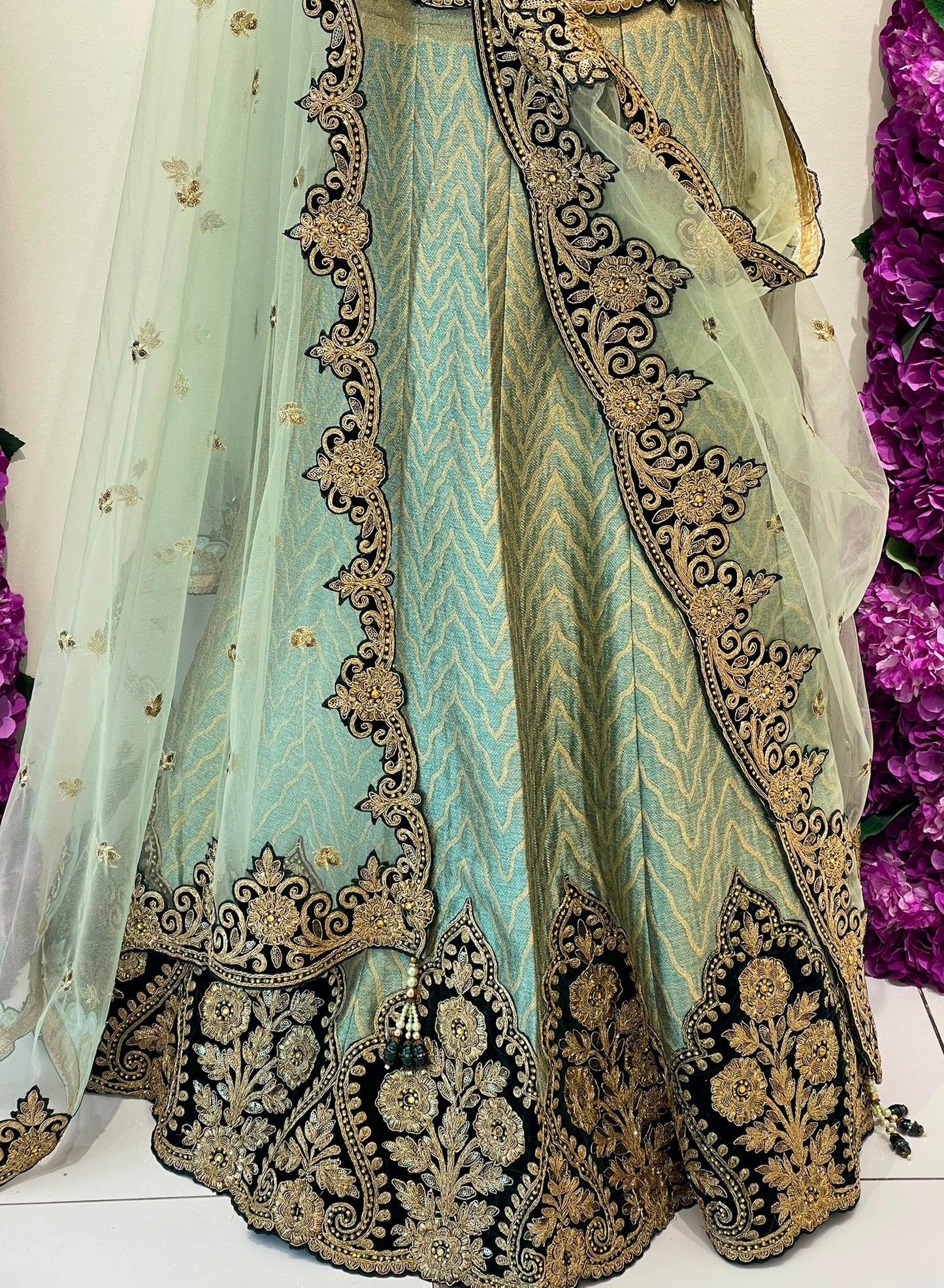 A light mint green traditional dress with elaborate Dark green and gold embroidery, shown with a matching sheer dupatta draped over one side.