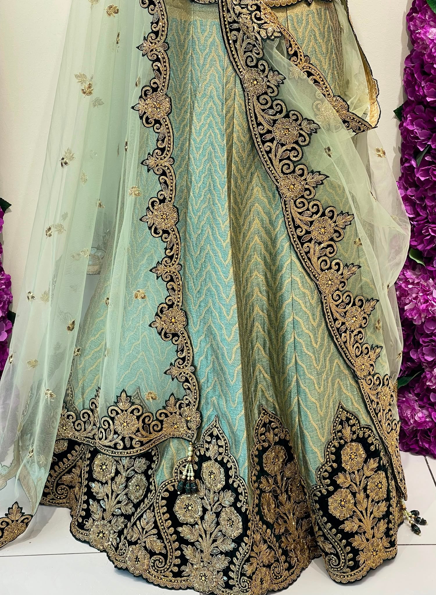 A light mint green traditional dress with elaborate Dark green and gold embroidery, shown with a matching sheer dupatta draped over one side.
