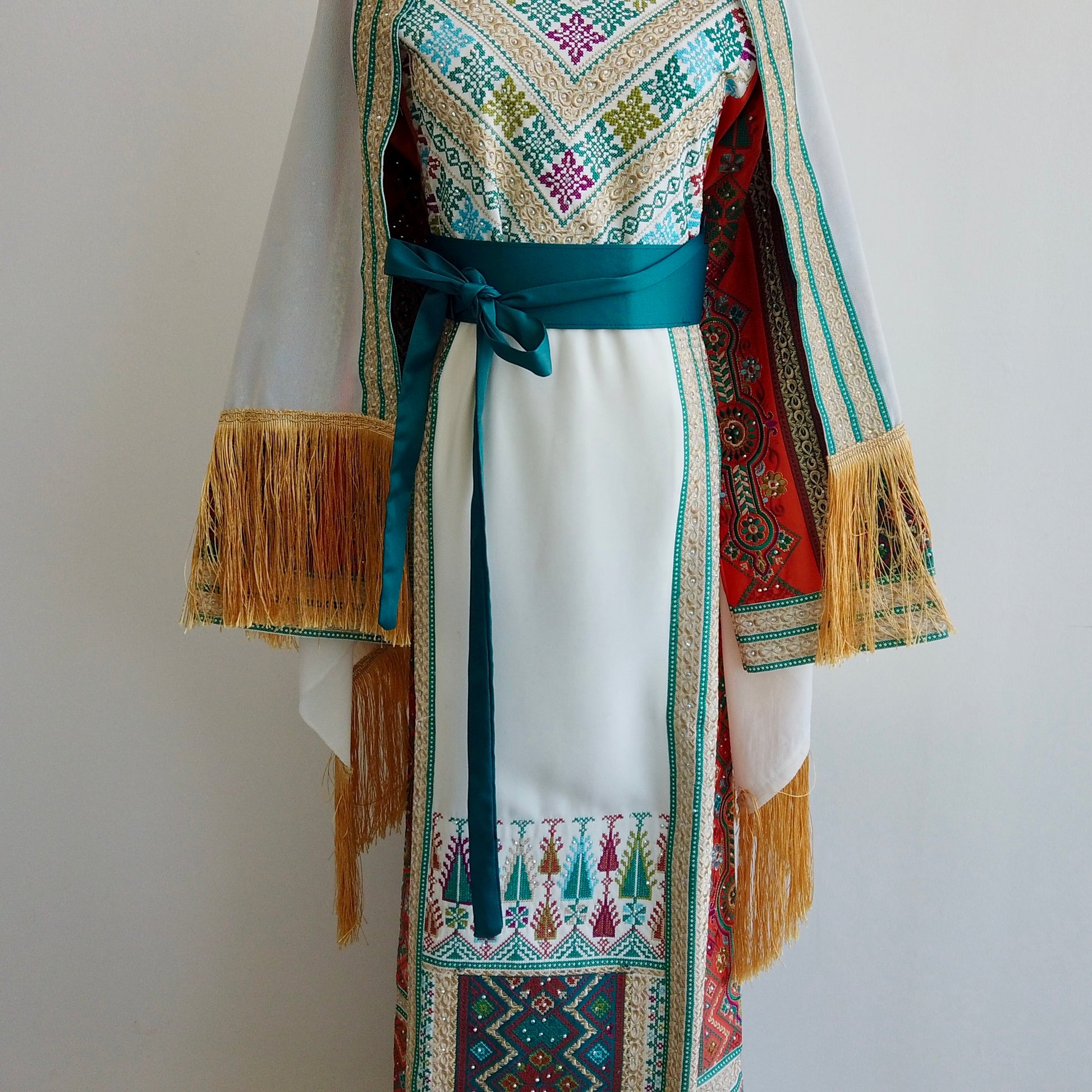 Front view of traditional embroidered thobe with teal belt and modest silhouette