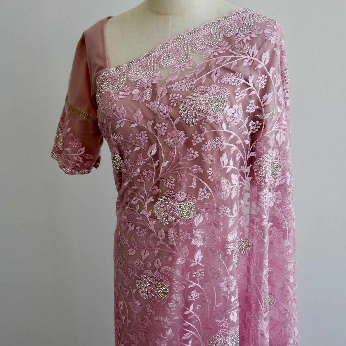 Close-up of floral threadwork and sequin design on pink net saree