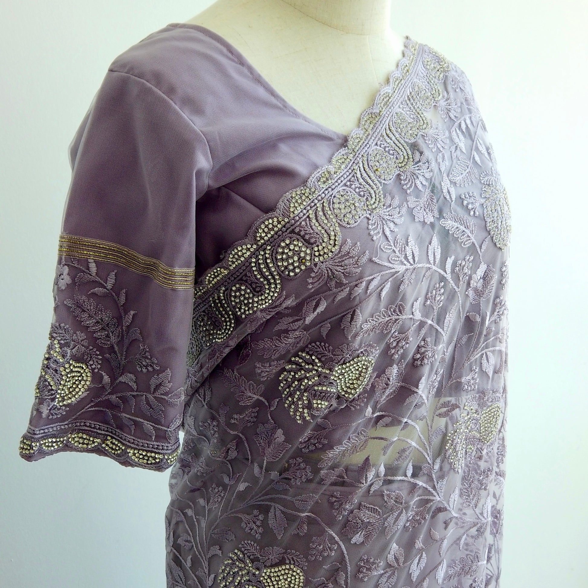 Embroidered purple blouse with floral patterns on a mannequin against a white background