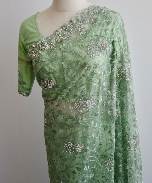 Green net ready-to-wear saree with silver floral embroidery displayed on a mannequin.