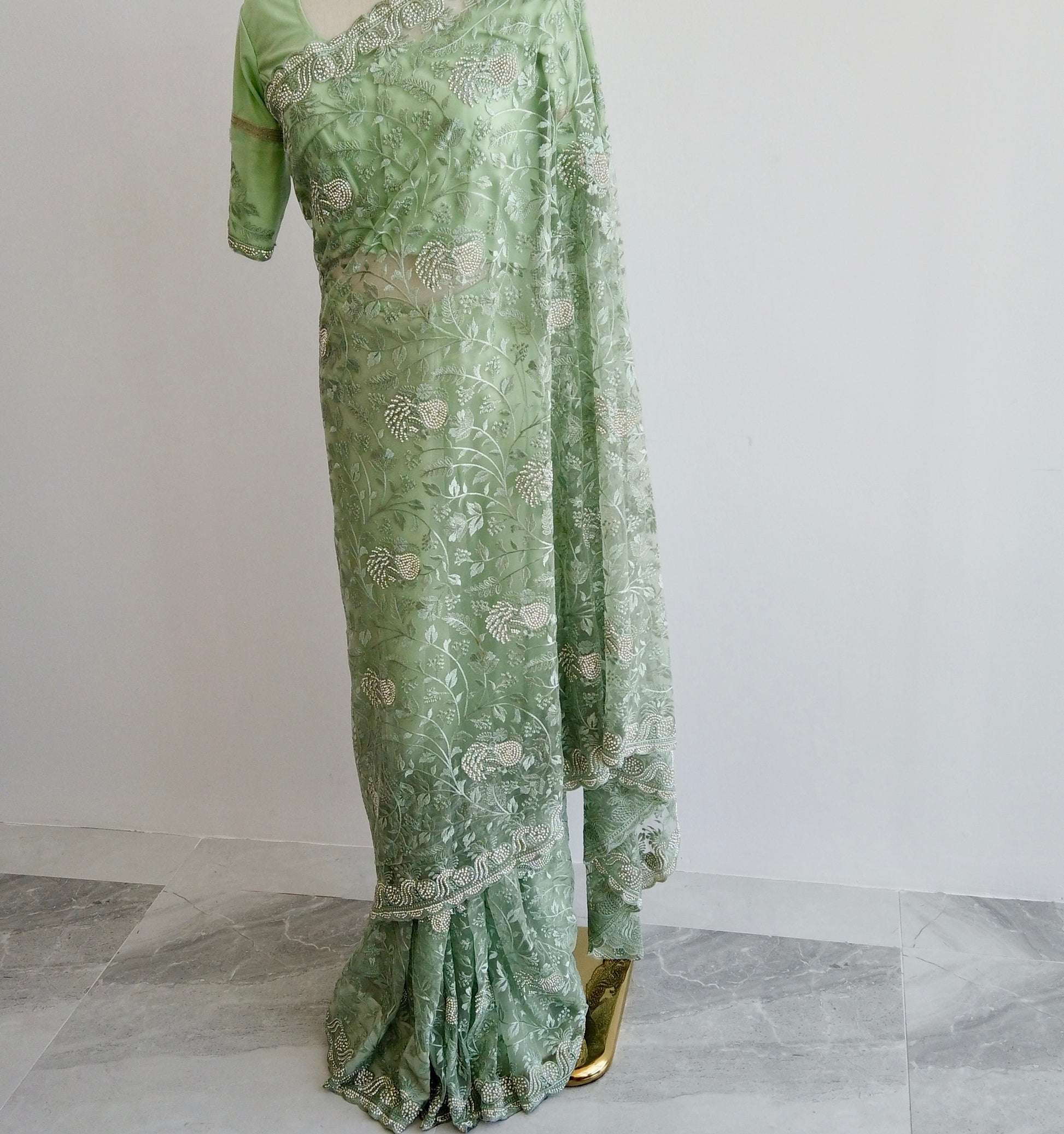 Full-length view of green embroidered net ready to wear saree showing pre-stitched pleats and elegant pallu