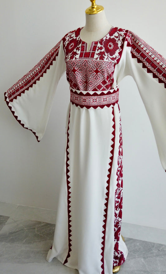Front-facing view of Palestinian thobe with red geometric embroidery and flowing silhouette displayed on mannequin
