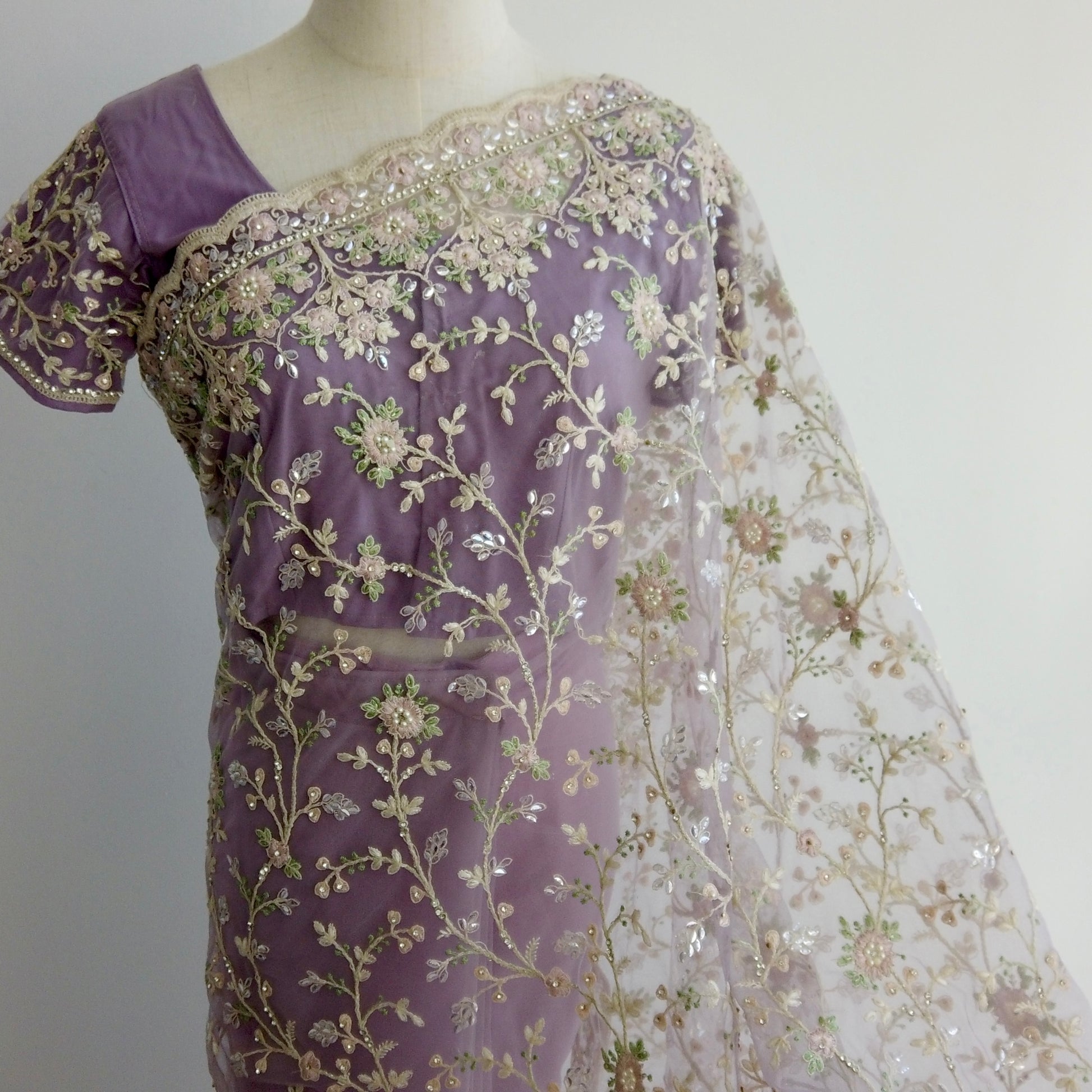 Purple net ready-to-wear saree with gold floral embroidery displayed on a mannequin