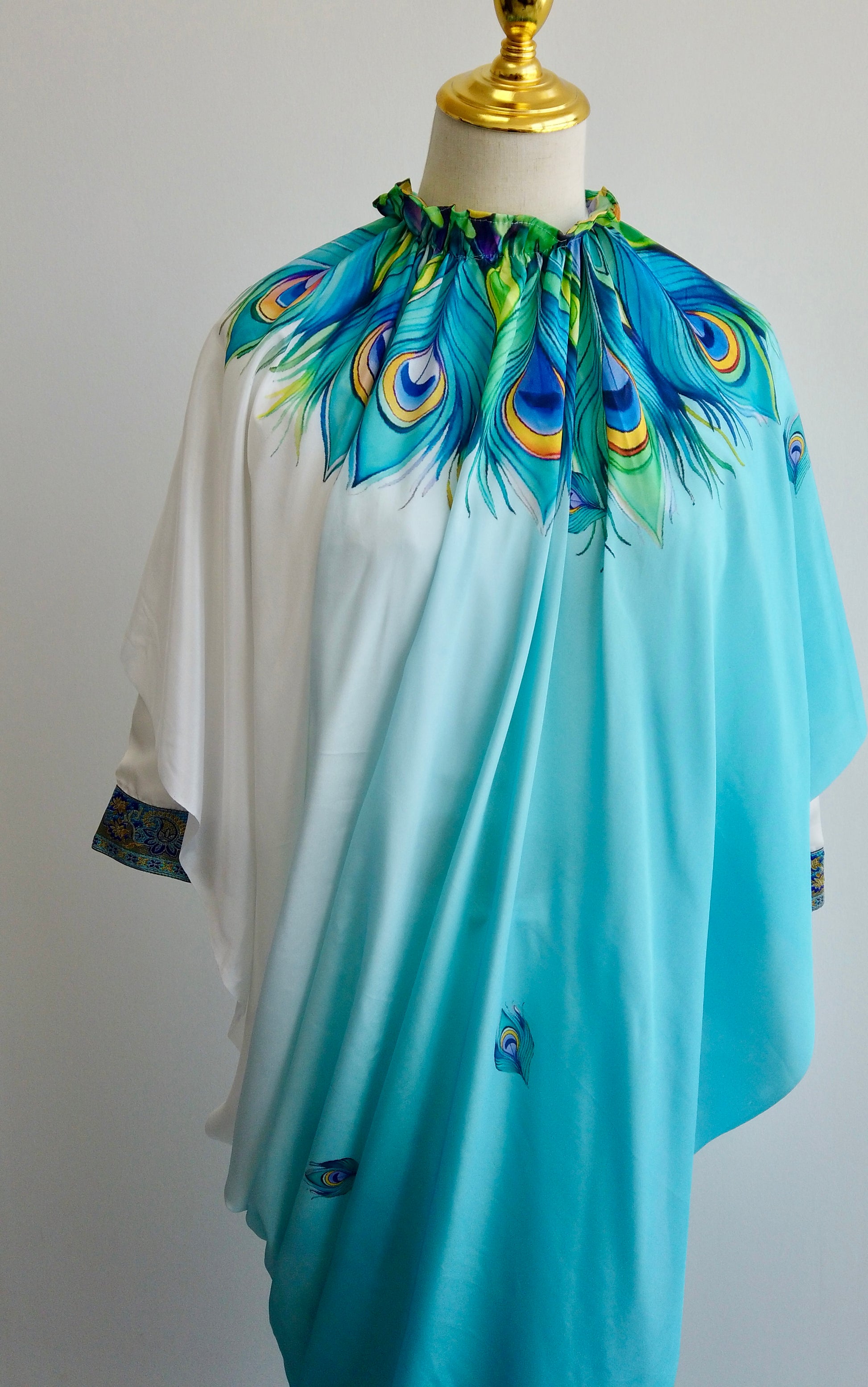 Turquoise and white kaftan-style ready-to-wear saree with peacock feather motifs and stitched blouse displayed on a mannequin.