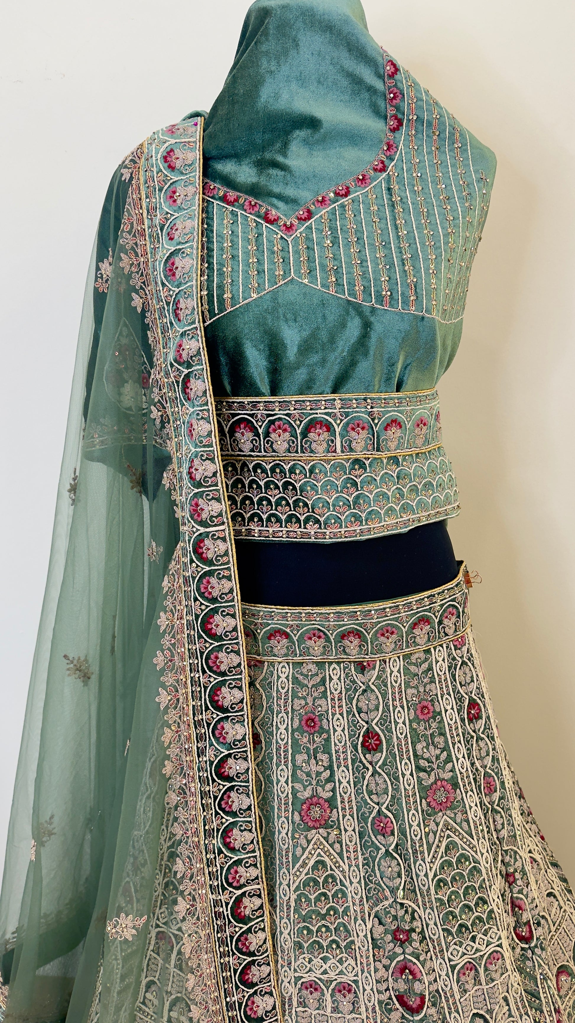 Traditional embroidered outfit with a green blouse and black dupatta on a white background