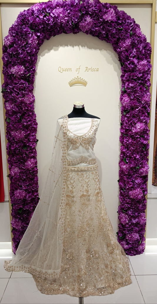 ivory white lehenga crafted from premium net and embroidered lace fabric, adorned with luxurious gold thread embroidery, sequins, and intricate bead detailing.