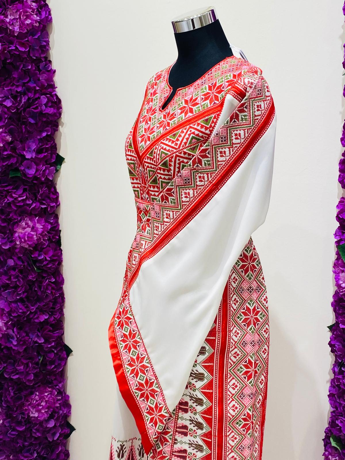 ivory Palestinian thobe at Arisca, detailed with red geometric embroidery.