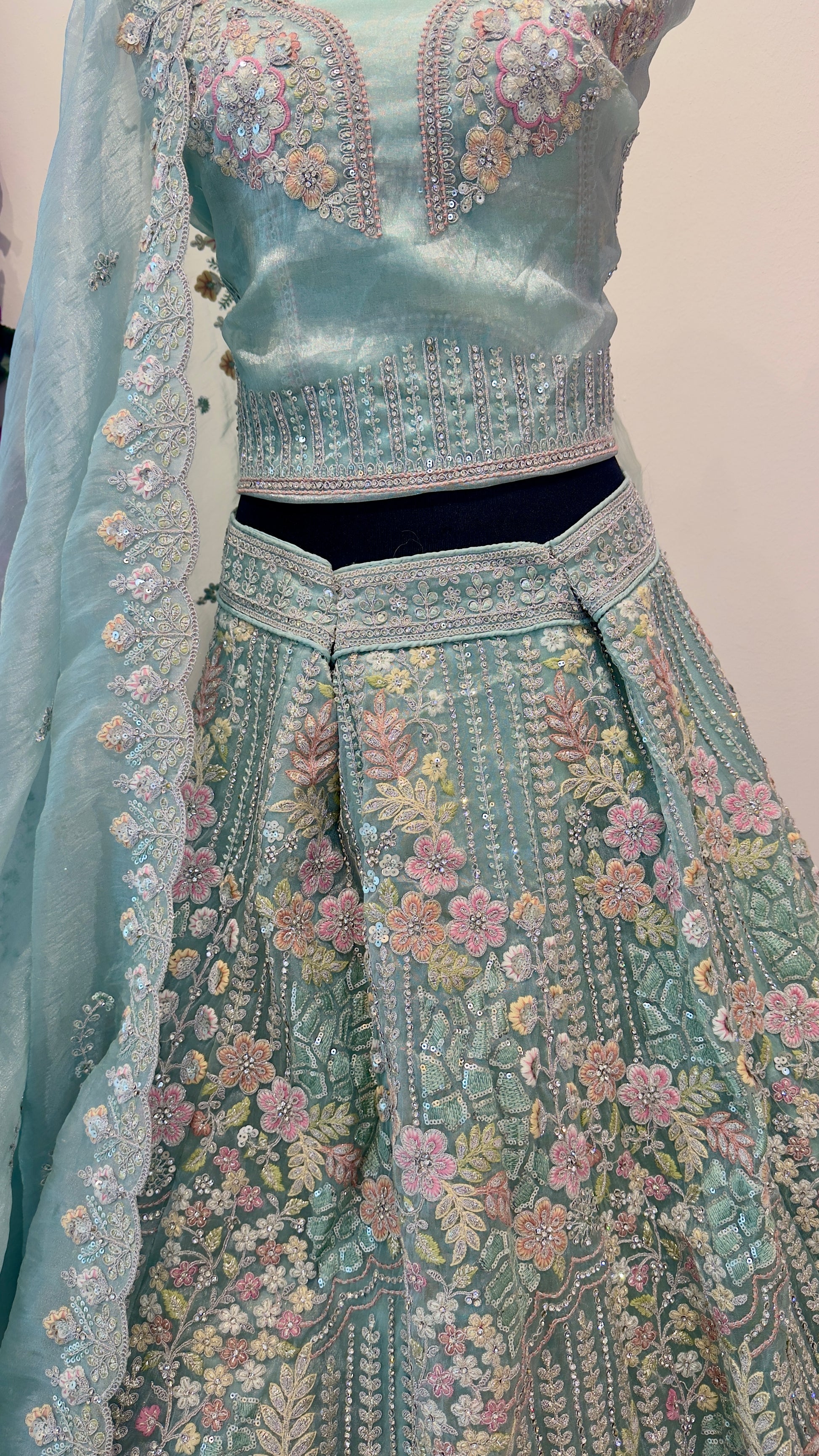 Traditional embroidered outfit with a light blue blouse and matching dupatta on a plain background