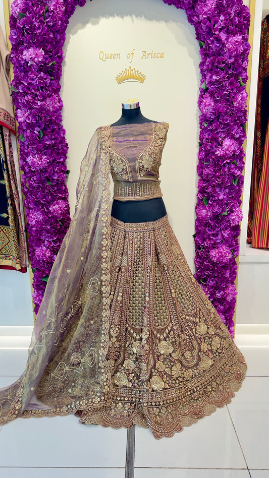 Delicate embroidered lehenga with a matching blouse on a mannequin against a decorative purple floral background.