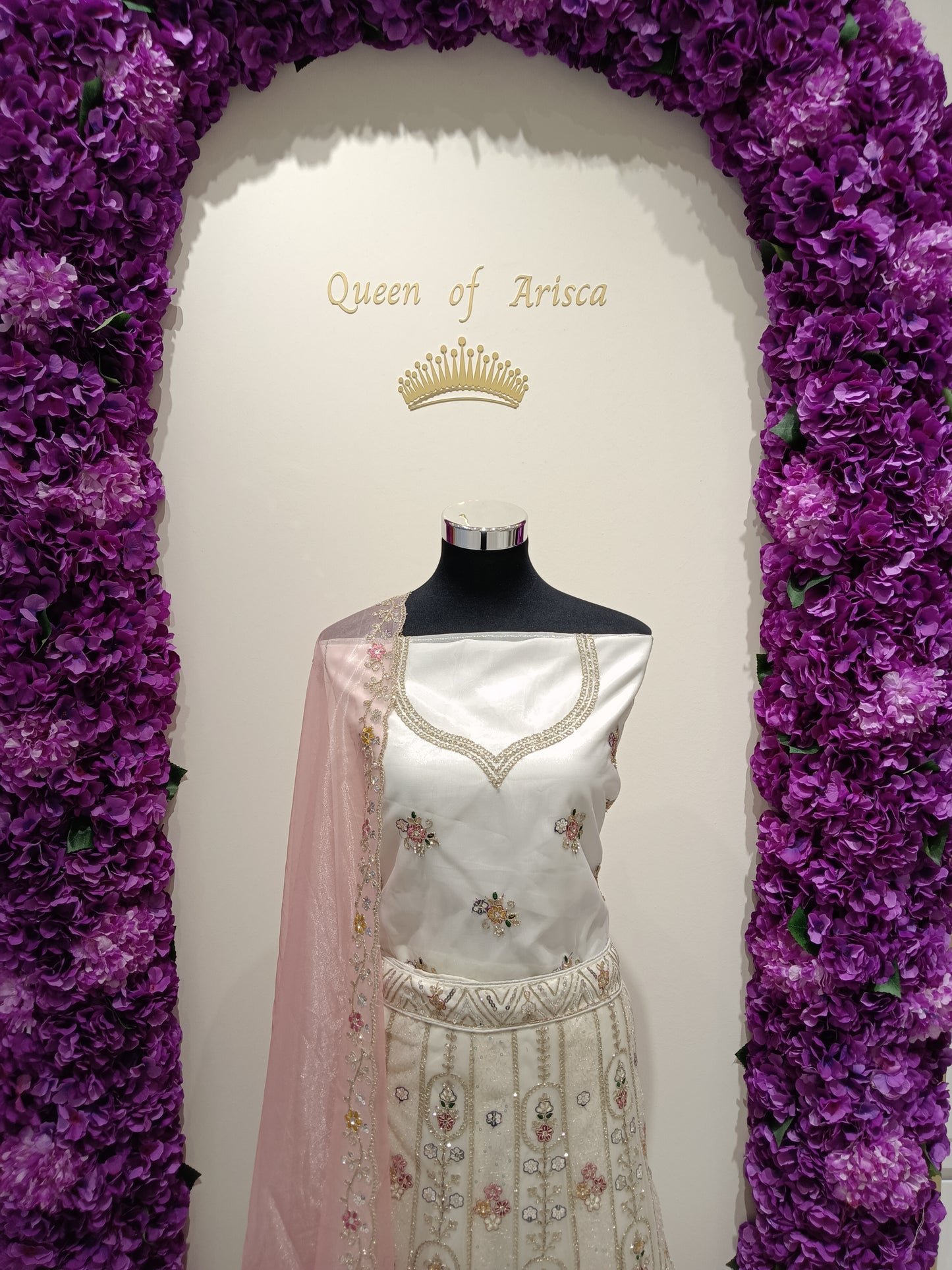 combination of pearl ivory tones with soft blush pink detailing gives the outfit a sophisticated royal aesthetic while maintaining a light, modern bridal look.