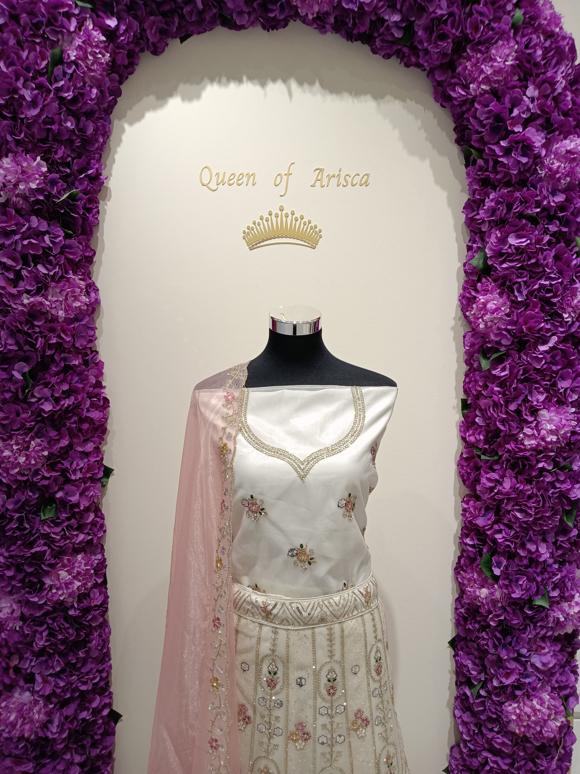 combination of pearl ivory tones with soft blush pink detailing gives the outfit a sophisticated royal aesthetic while maintaining a light, modern bridal look.