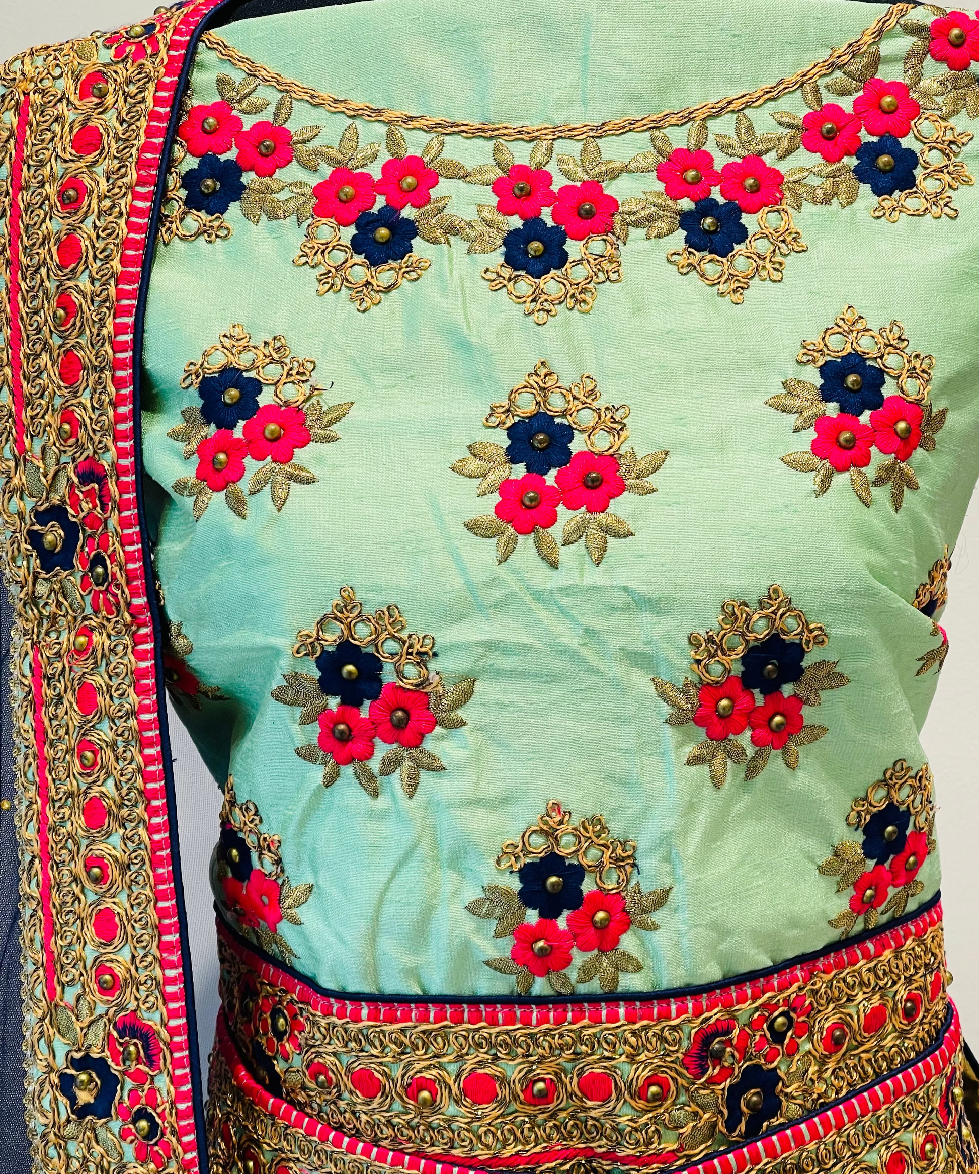 A mint green embroidered blouse , featuring vibrant pink, navy blue, and gold floral embroidery with a matching embroidered border and dupatta.