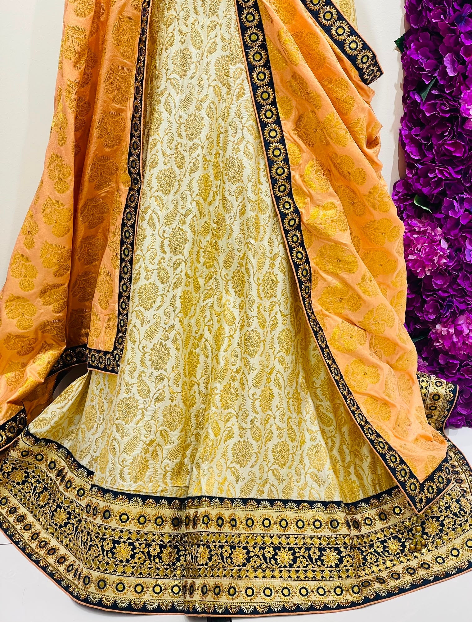 A traditional Indian ethnic outfit featuring a light yellow and gold brocade skirt with a wide navy blue and gold border, paired with a matching yellow dupatta draped over the shoulders.