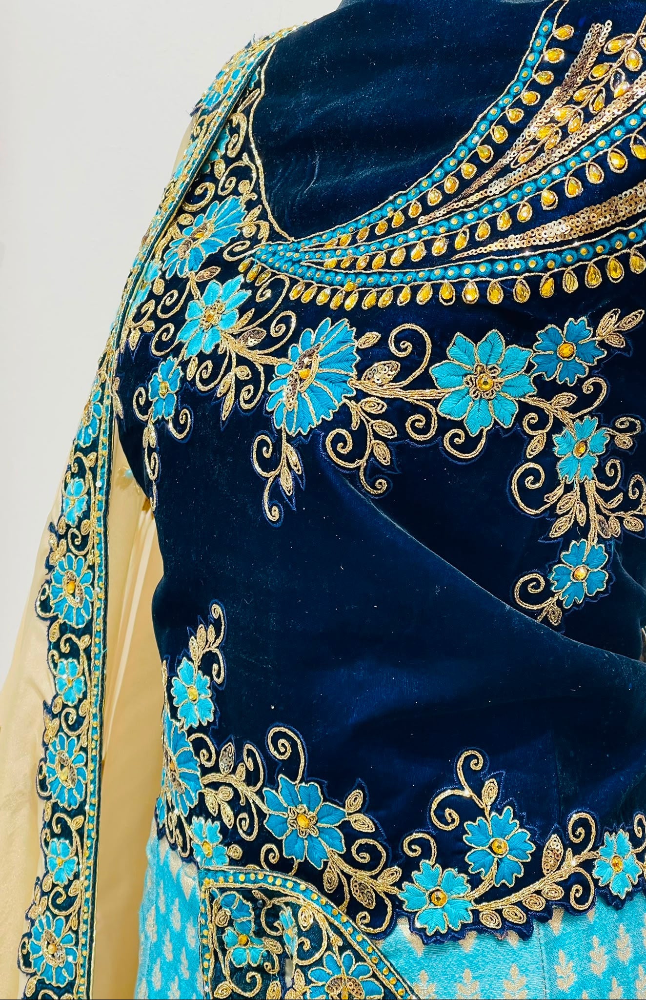 Close-up of a navy blue velvet embroidered blouse with turquoise blue and gold floral embroidery, paired with a light beige dupatta.
