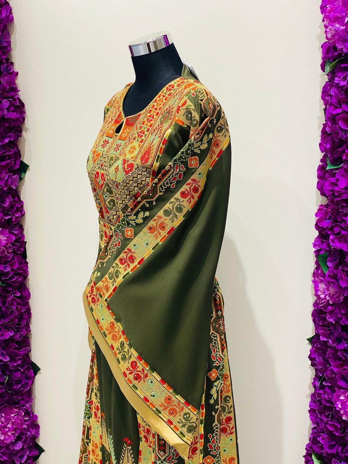Olive green Palestinian-inspired thobe with colourful geometric embroidery at Arisca Qatar.