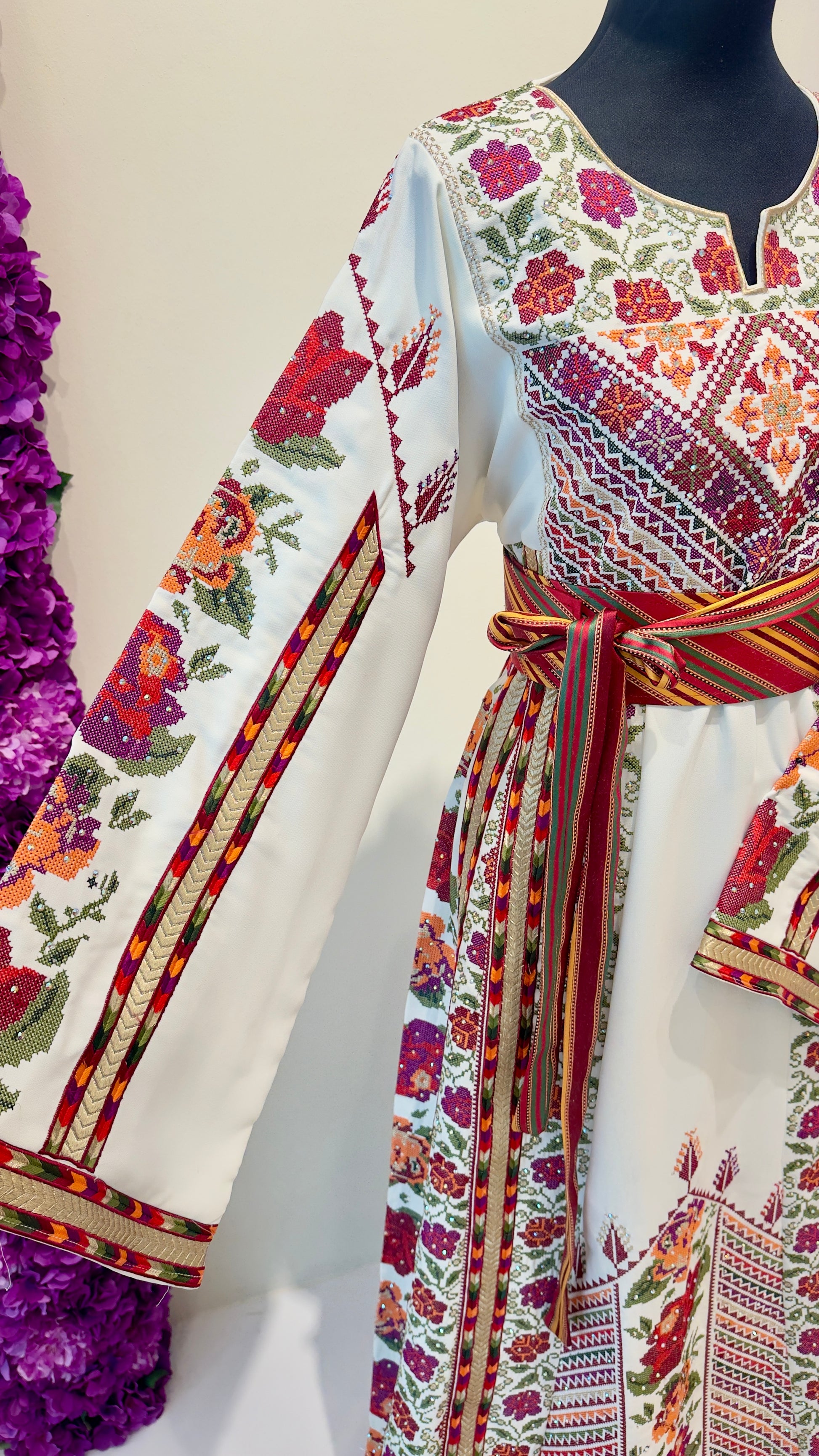 Traditional embroidered dress on a mannequin with a floral background