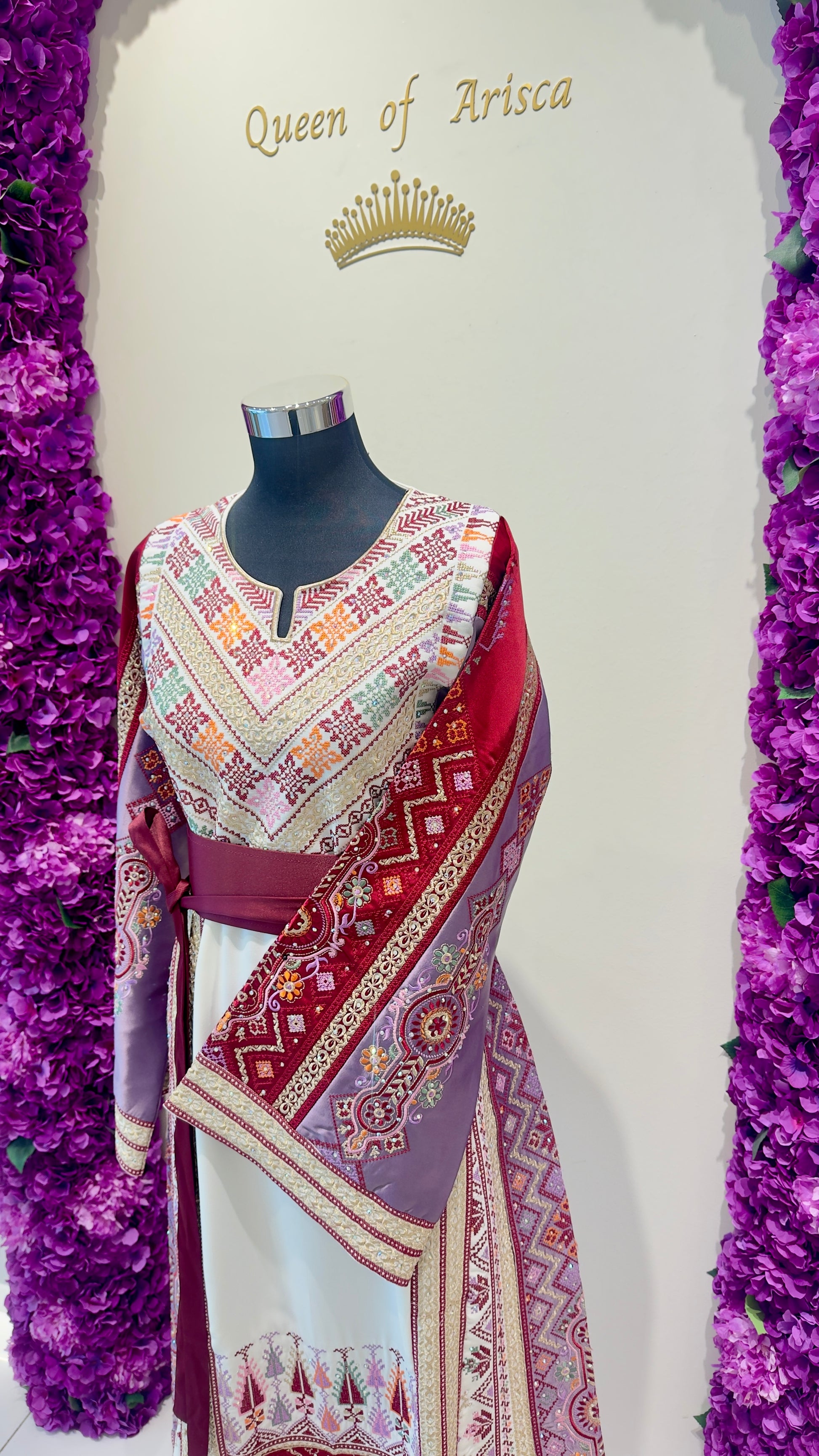 Mannequin wearing a tatreez dress with 'Queen of Arisca' text and crown on a white background.