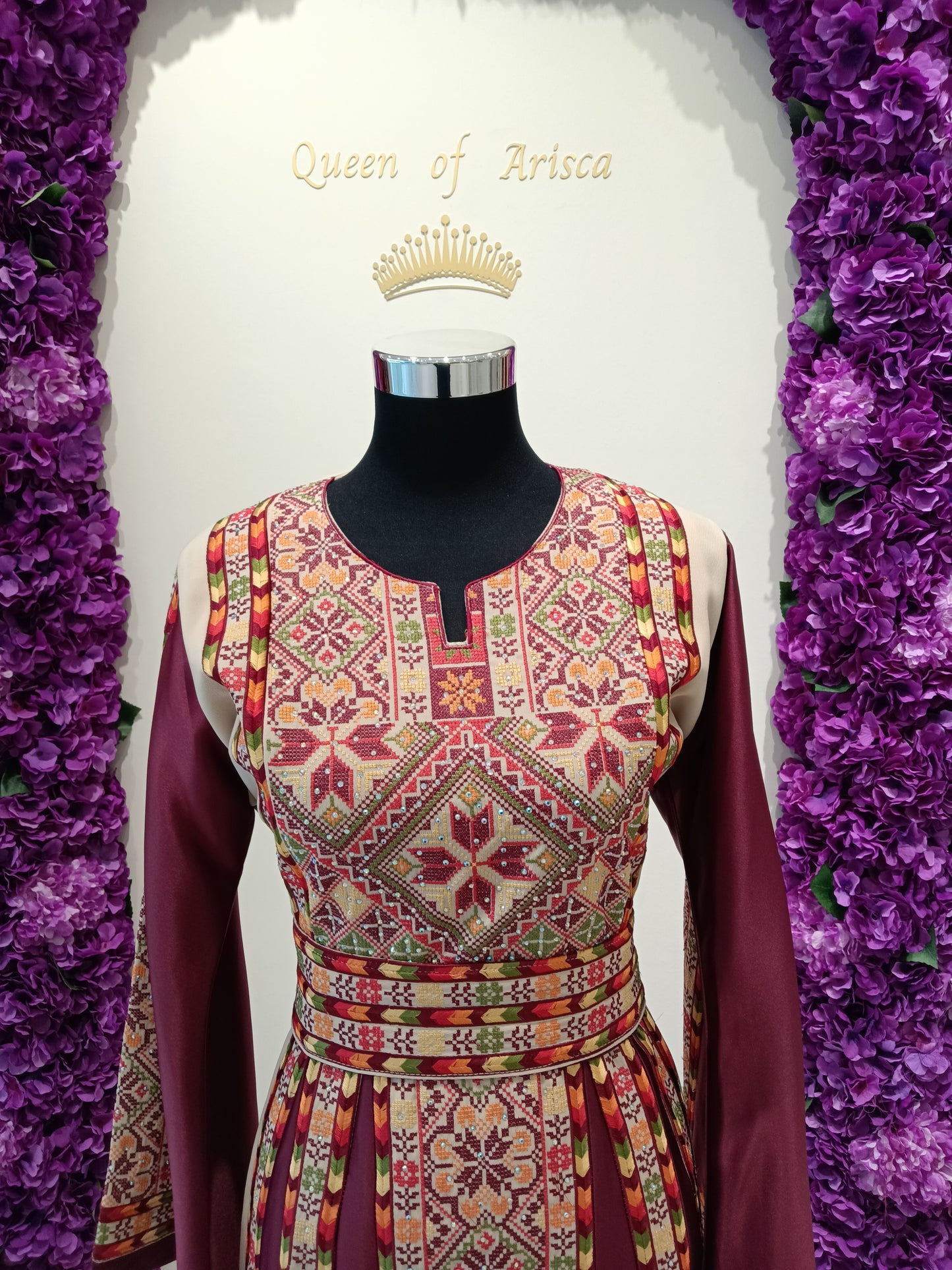 rich deep maroon (burgundy) thobe, beautifully contrasted with intricate multicolor embroidery in shades of beige, gold, olive green, and soft coral.