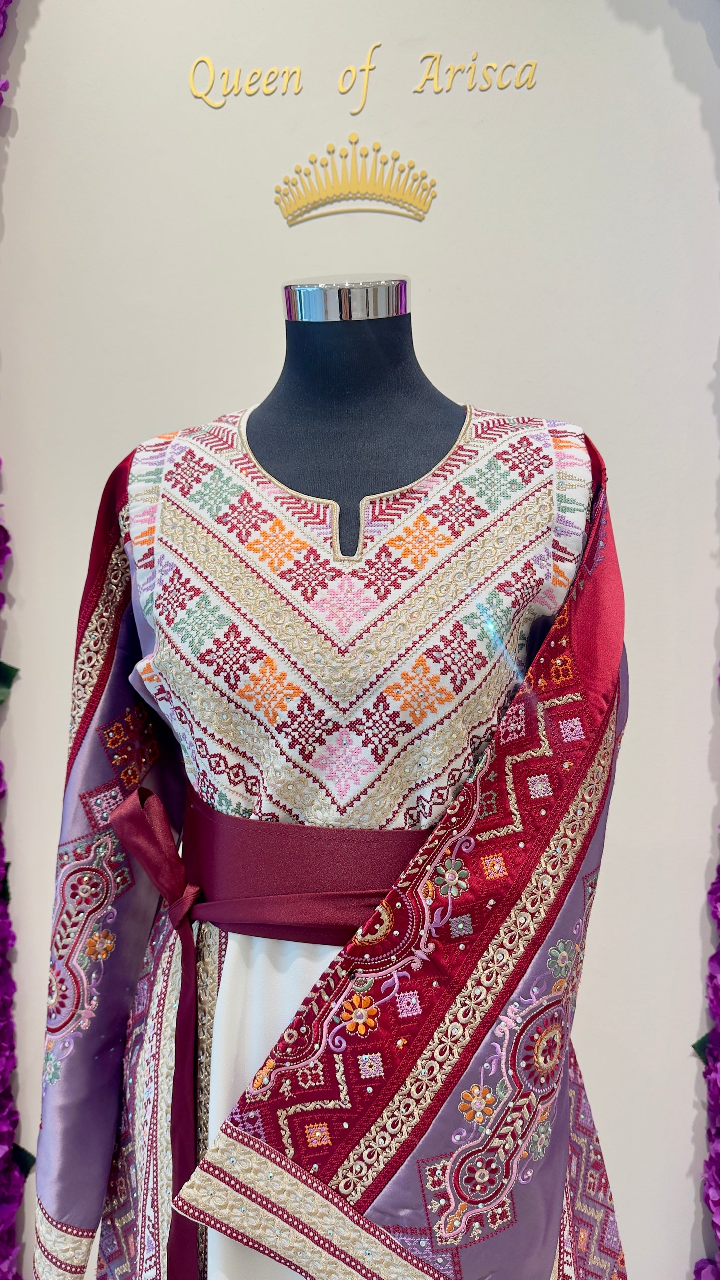 Mannequin wearing a colorful embroidered thobe with a 'Queen of Arisca' label.