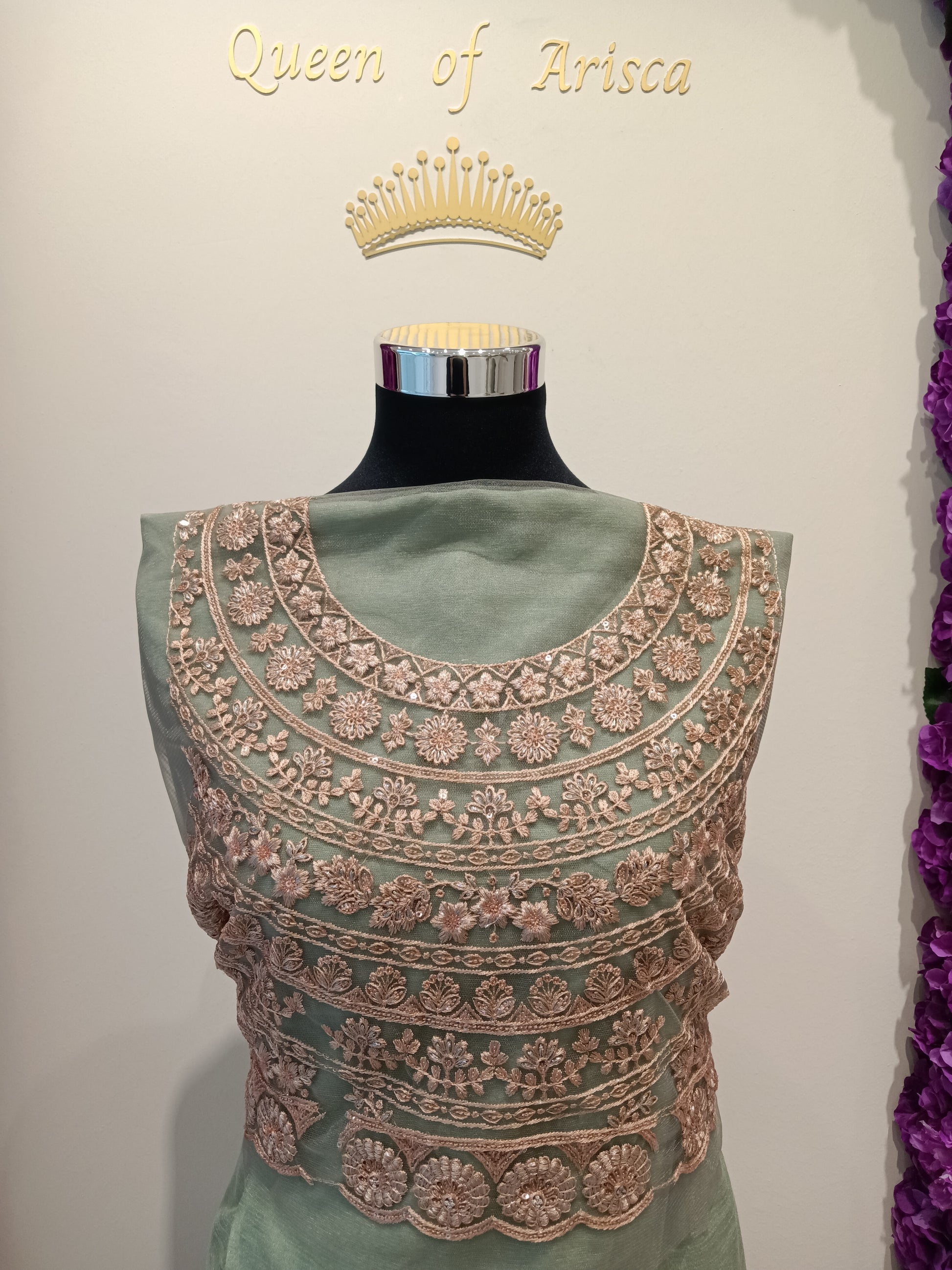 modern royal esthetic saree blouse,base color is a muted sage green / pastel pistachio, The embroidery is done in a rose gold / antique gold tone, creating a beautiful contrast that looks luxurious without being too loud.