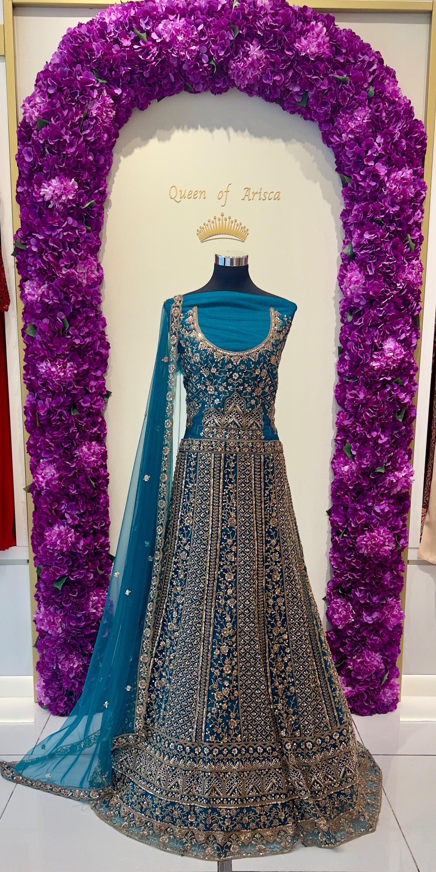 peacock teal lehenga showcases dense antique gold zari and stone embroidery across vertical panels.
