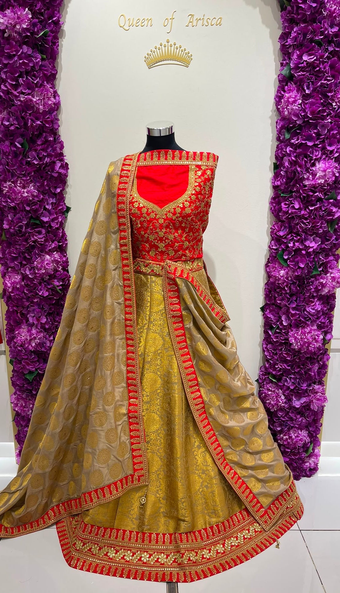 A traditional Indian lehenga . The outfit features a gold-colored skirt with red and gold borders, a red sleeveless blouse with gold embroidery, and a matching sheer dupatta draped over the skirt.