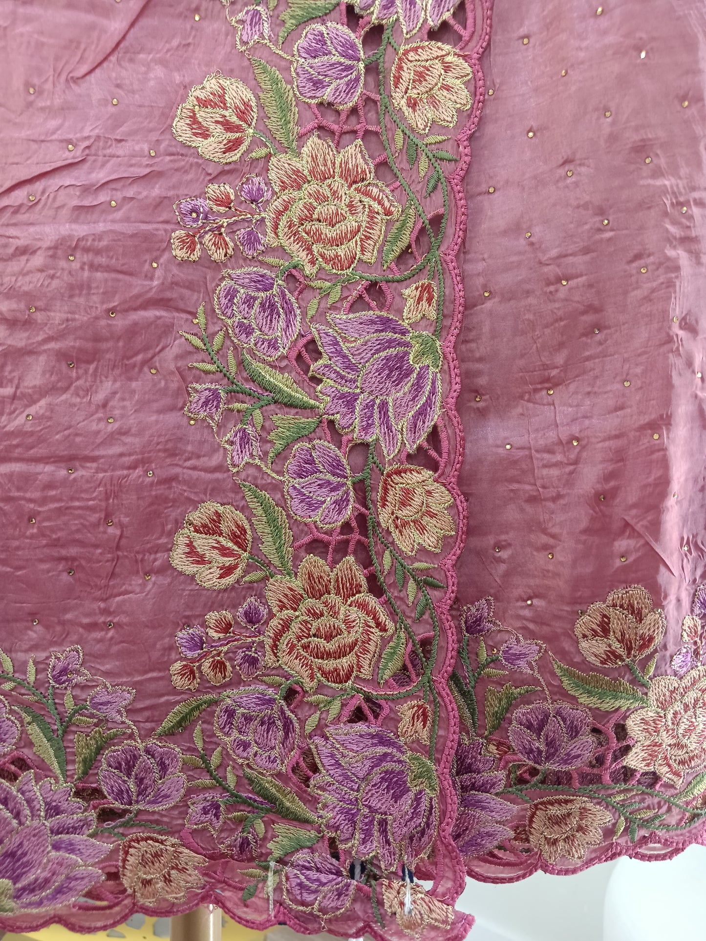Close-up of embroidered saree with floral patterns on a pink fabric