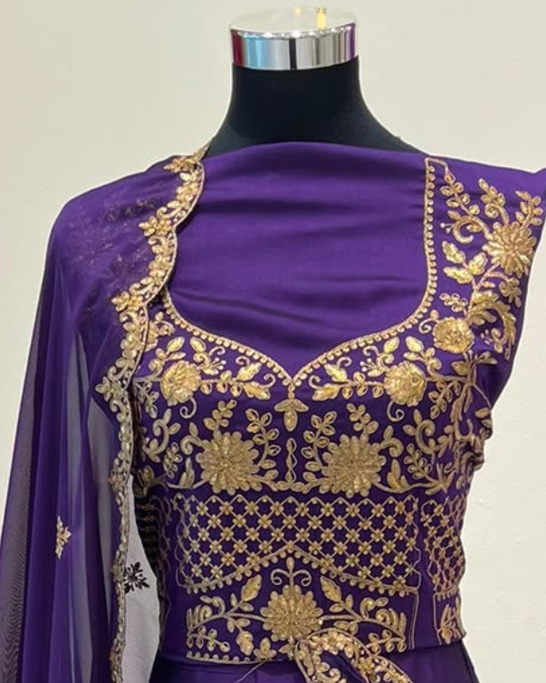 A purple traditional lehenga blouse decorated with gold embroidery and a matching sheer dupatta.  