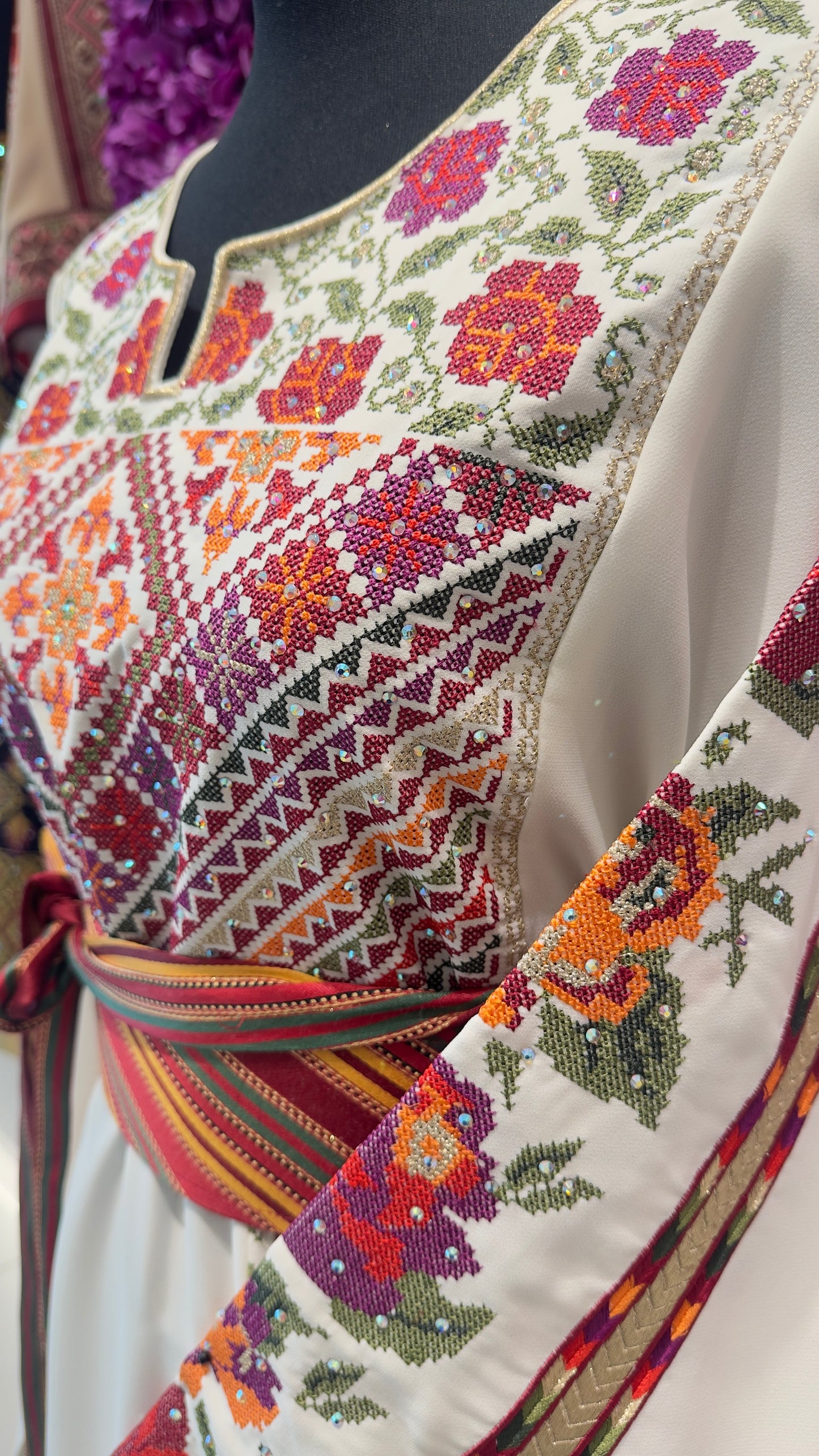 Colorful embroidered garment with floral and geometric patterns on a mannequin.