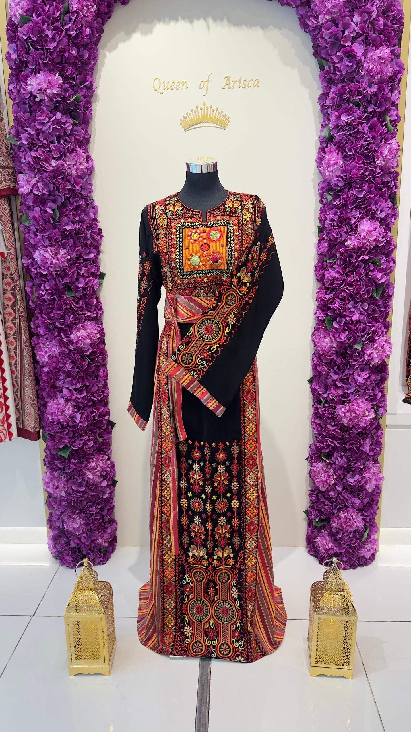 Decorative thobe on a mannequin with floral arrangements and lanterns in the background