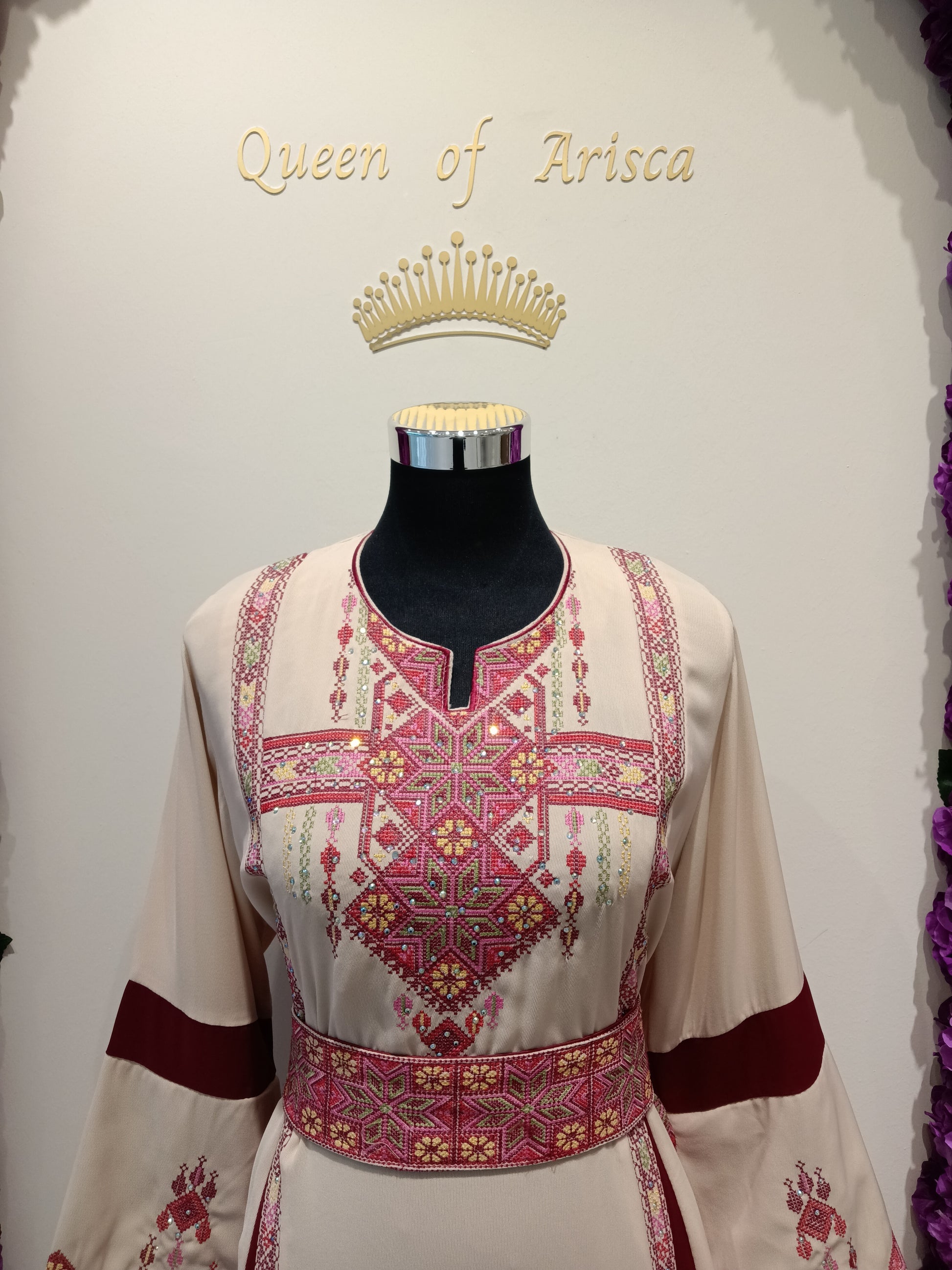 Discover the elegance of a Palestinian thobe with cream fabric, maroon panels, and gold embroidery.