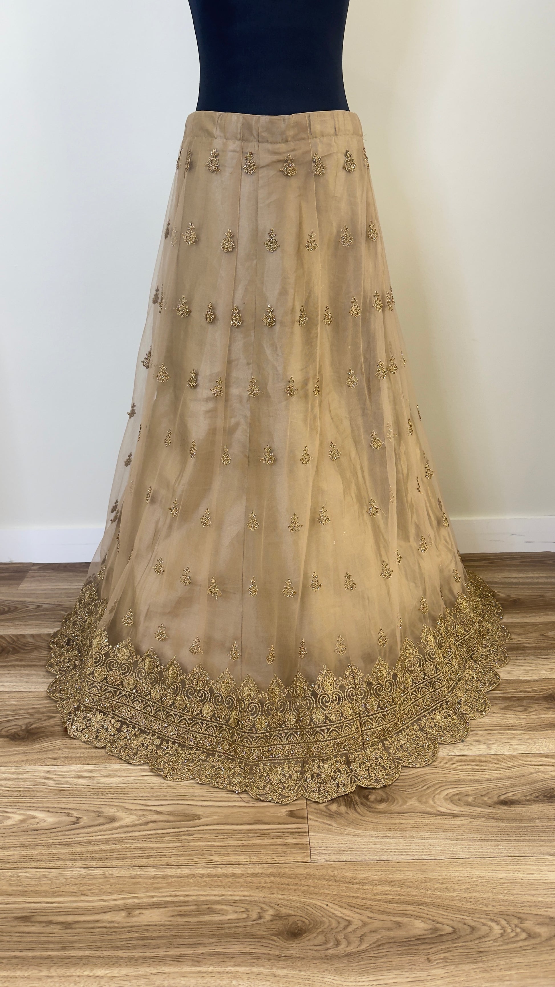 Golden embroidered skirt on a wooden floor with a white wall background