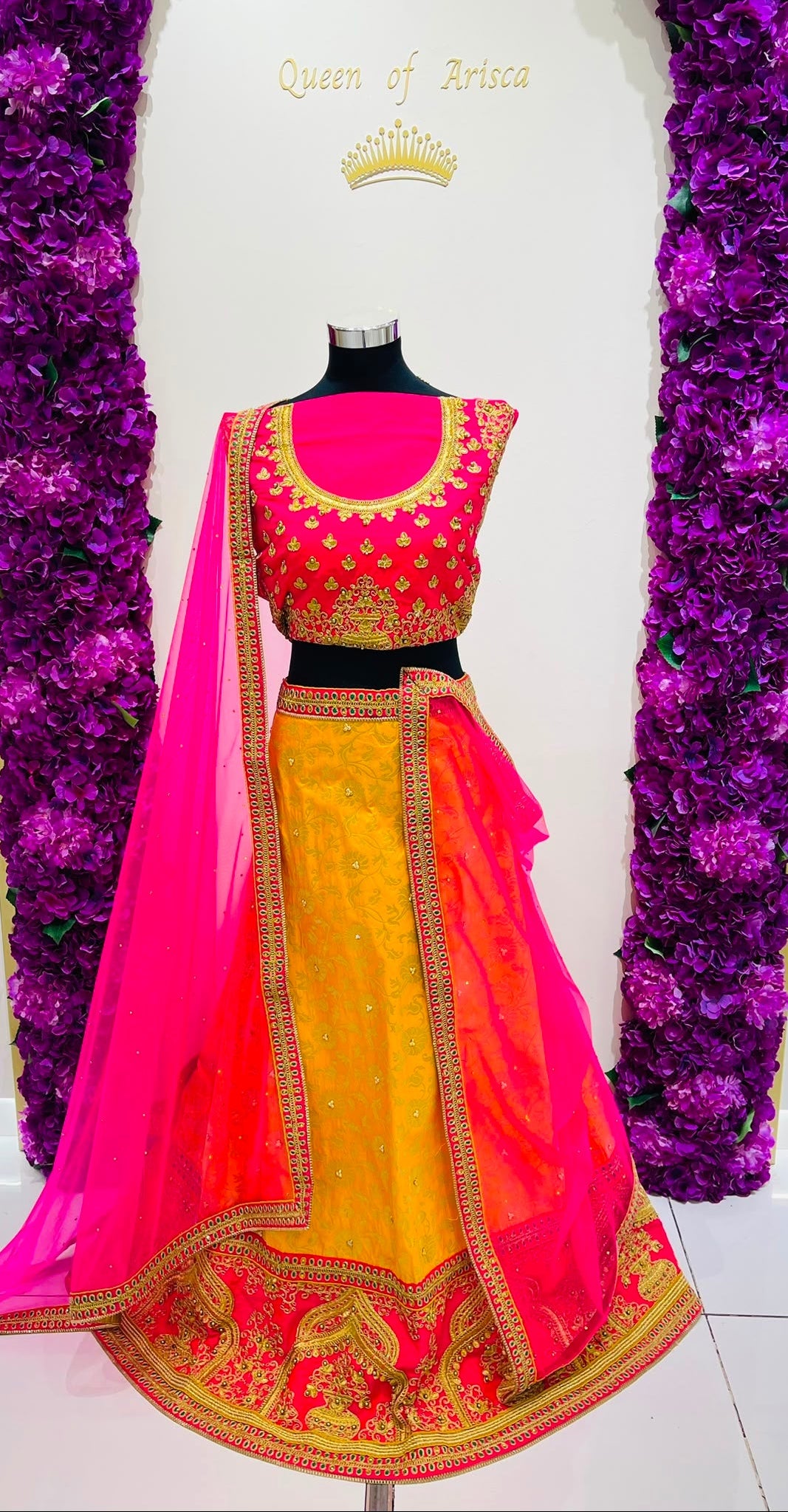 A vibrant Indian party wear set , featuring a bright pink and yellow lehenga  with intricate gold embroidery.