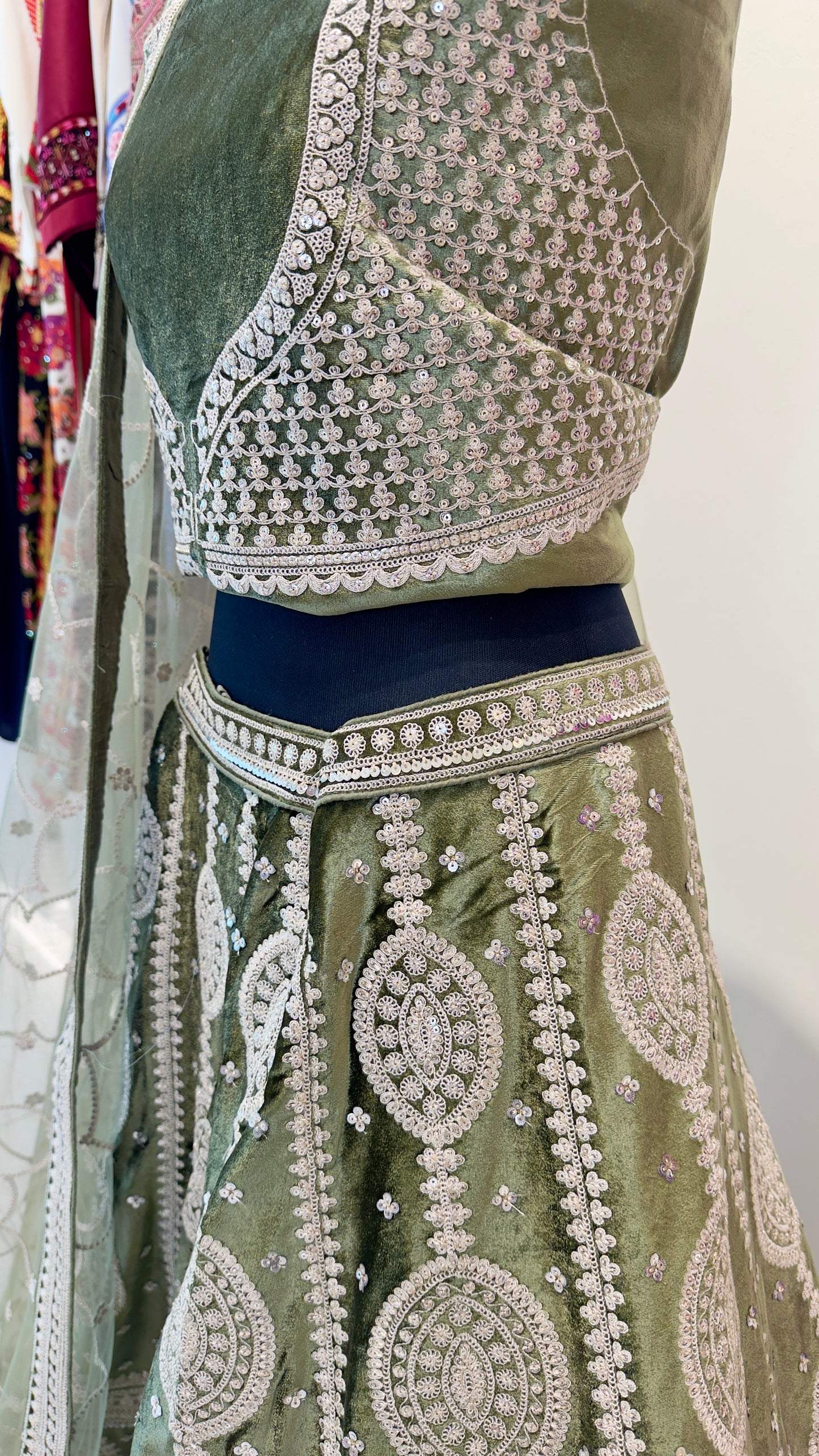 Traditional outfit with green top and skirt featuring intricate white embroidery on a plain background.